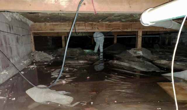 Crawl space with standing water and moisture damage, showing insulation and structural concerns before repair.