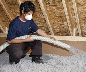 Man installing blown-in cellulose insulation in an attic.