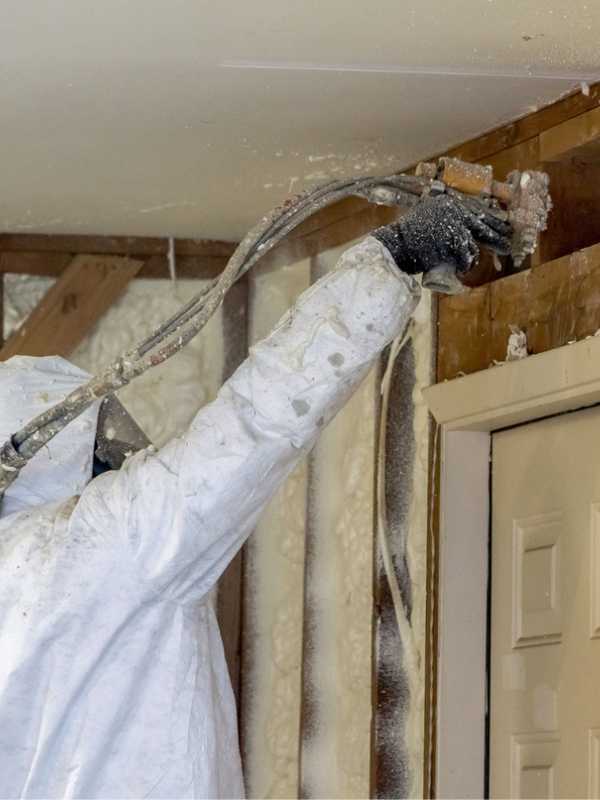 Worker installing spray foam insulation in remodeled home.