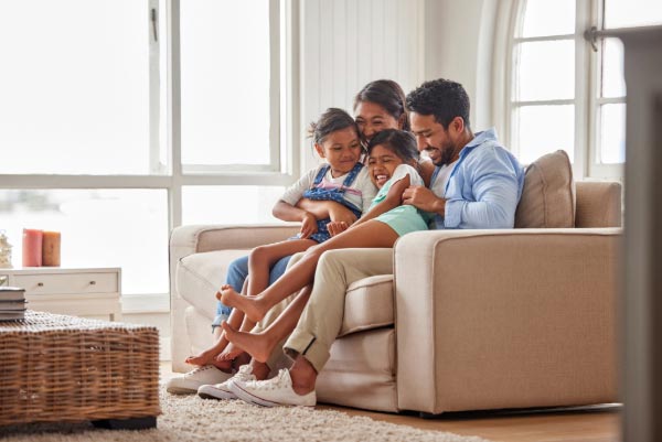 Happy Florida family, hugging and laughing together on couch.