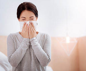 woman blowing nose due to indoor allergies