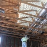 Worker installing spray foam insulation on a ceiling.
