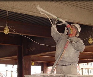 Man spraying fireproofing material onto a ceiling.