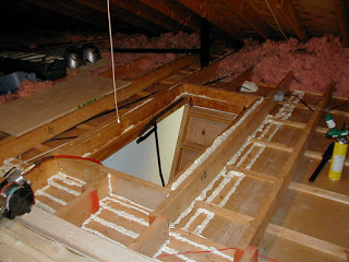 Air sealing on an attic floor and doorway.